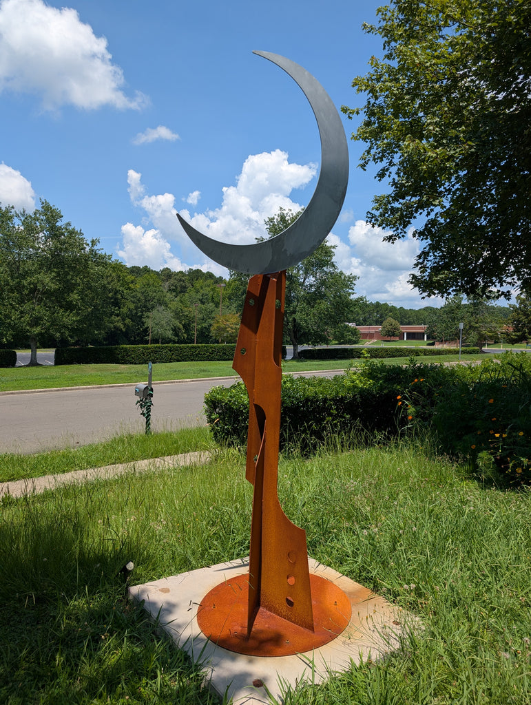 Metal sculpture of a crescent moon on a base with Big Dipper constellation cut-out pattern